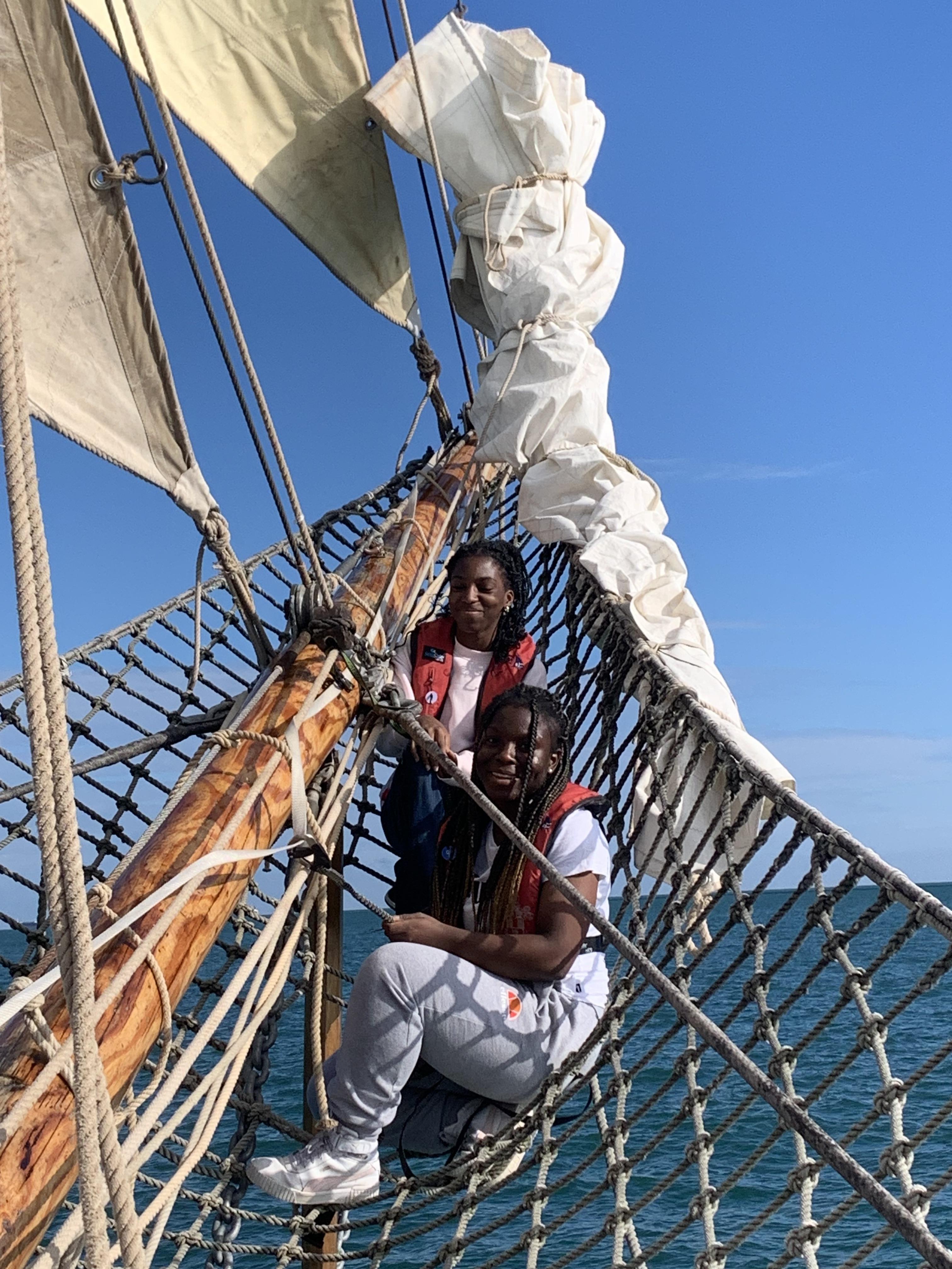 Two girls sitting in the netting by Queen Galadriel's bowsprit