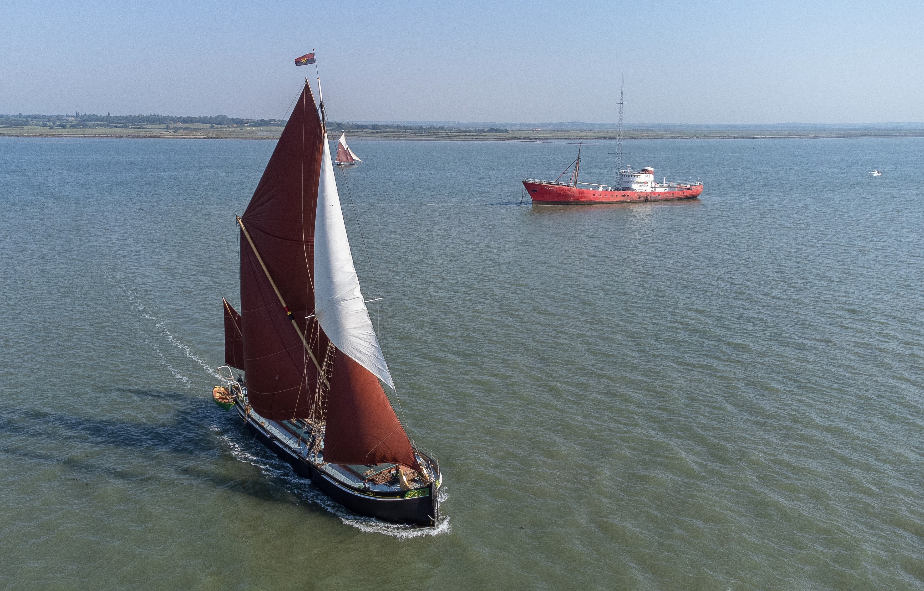 Pudge under full sail going towards bottom right of the photo, with Radio Caroline in the background