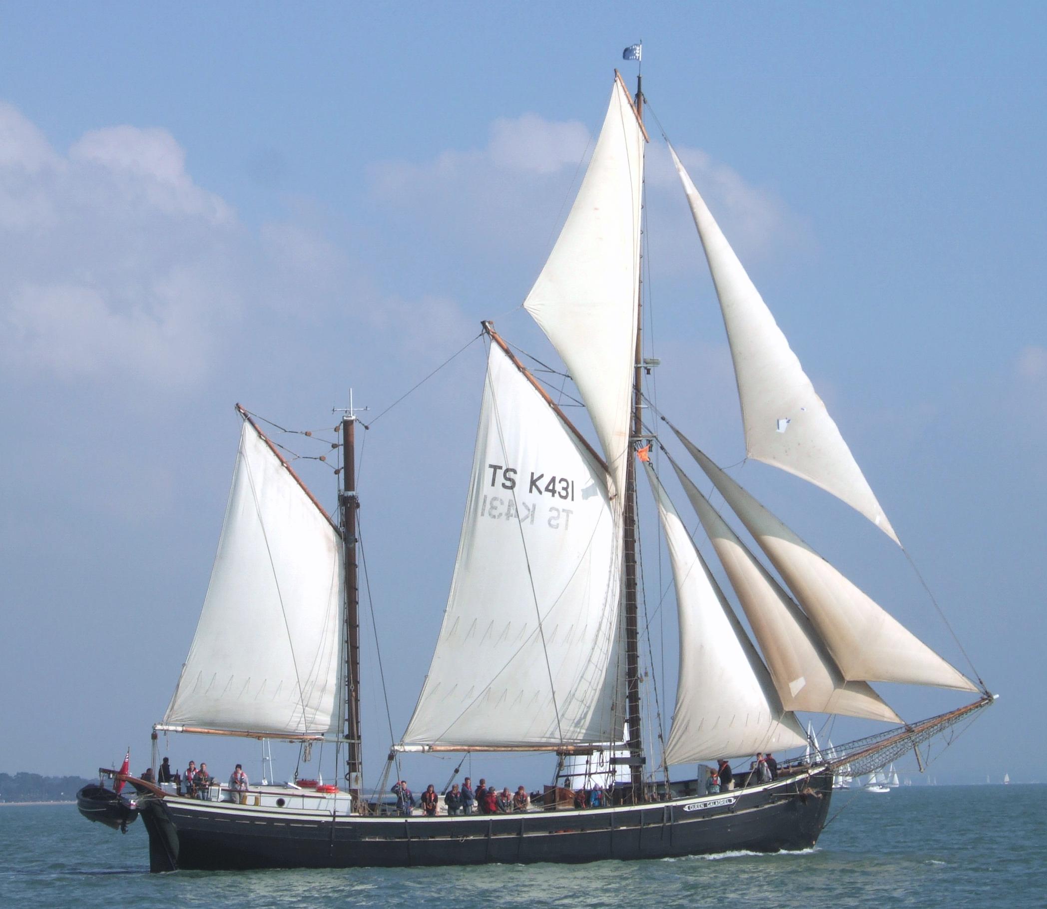 Starboard beam view of Queen Galadriel under full sail, with crew on deck and looking towards the camera