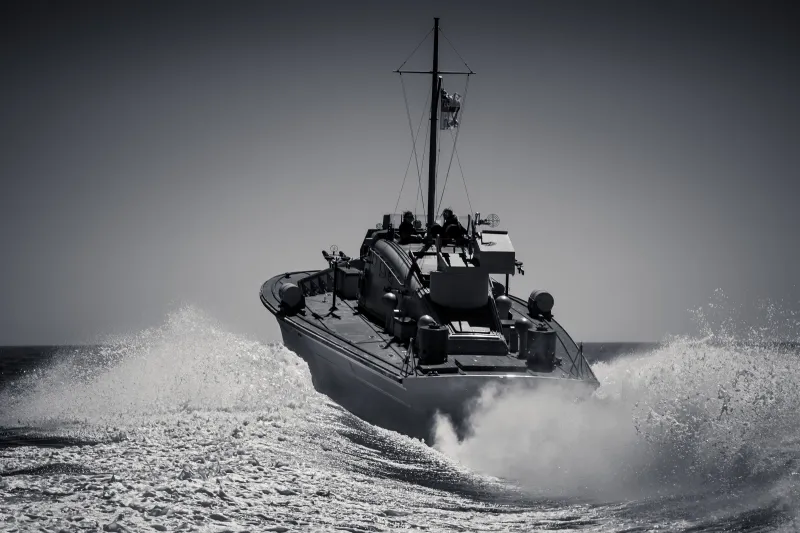 Black and white image of MGB81 from the stern going at considerable speed, the water behind her foaming and splashing