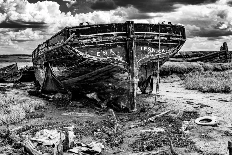 Black and white image showing the stern of the wreck of sailing barge Ena sitting on the mud at low water.