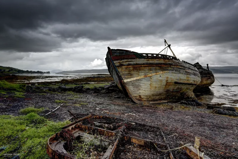 Abandoned boat lying on its side on a muddy shore