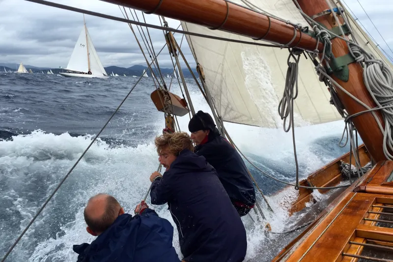 Deck view looking towards port side at three sailors hauling a line
