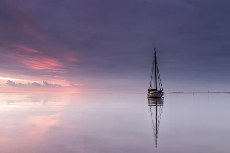Smack moored on a calm day, with the pink and purple sky reflected in the water below